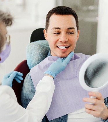 Man smiling at reflection in mirror with dentist