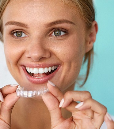 Woman smiling while holding teeth whitening tray