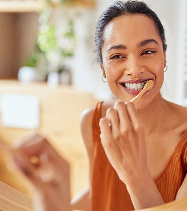 Woman smiling while brushing her teeth